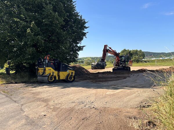 Ein Bild von der Baustelle mit Bagger und Walze