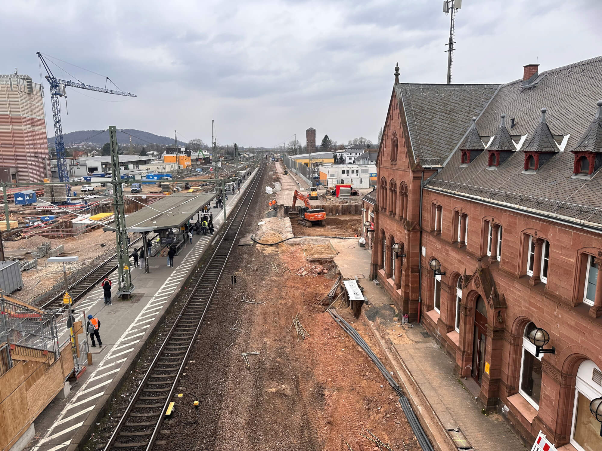 Ein roter Bagger am Bahnhof Gelnhausen gräbt am zukünftigen nördlichen Eingangsbereich der neuen Personenunterführung.