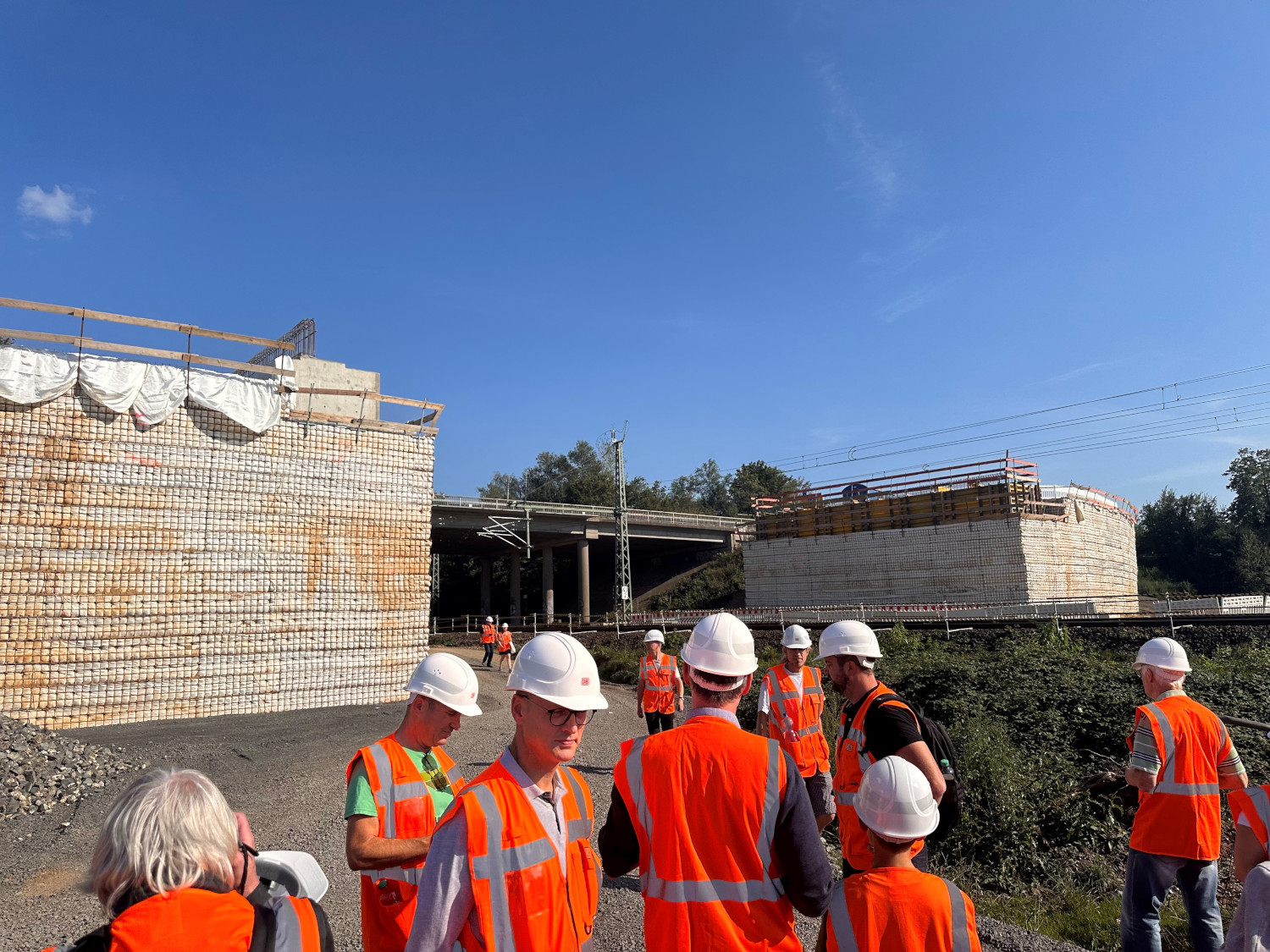 Besuchergruppe in Warnwesten und Helmen auf der Baustelle